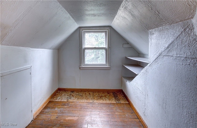 additional living space featuring vaulted ceiling and hardwood / wood-style flooring