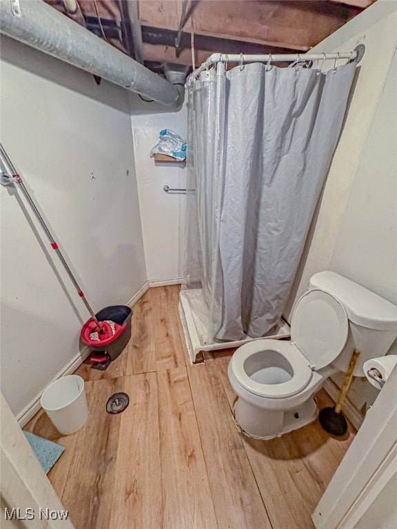 bathroom with toilet, wood-type flooring, and walk in shower