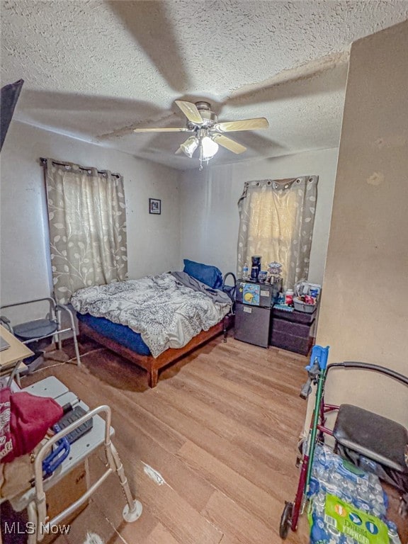 bedroom with ceiling fan, a textured ceiling, and wood-type flooring