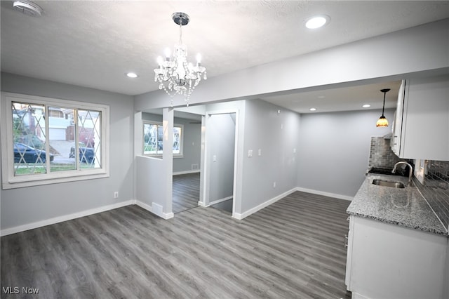 unfurnished dining area with dark wood-type flooring, a chandelier, a textured ceiling, and sink