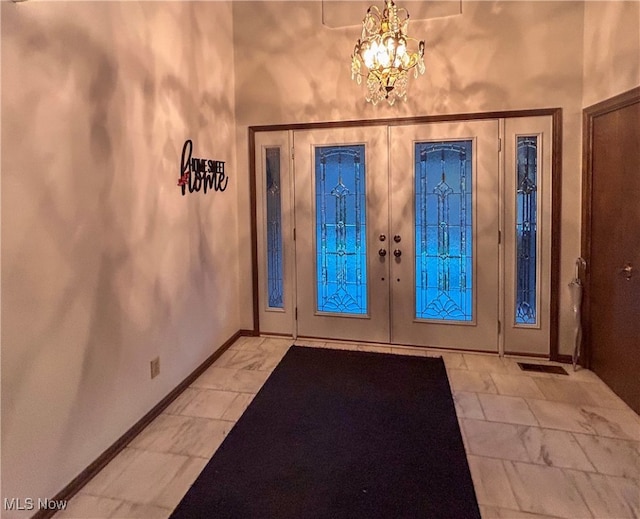 foyer entrance featuring french doors and a notable chandelier