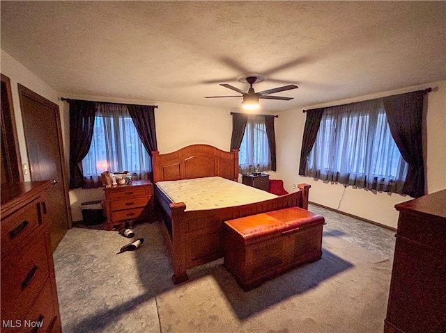 carpeted bedroom featuring ceiling fan and a textured ceiling