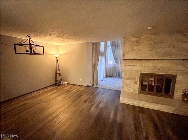 unfurnished living room with wood-type flooring, a textured ceiling, and a stone fireplace