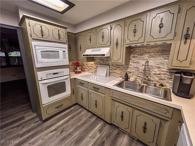 kitchen with decorative backsplash, dark hardwood / wood-style flooring, white appliances, and sink