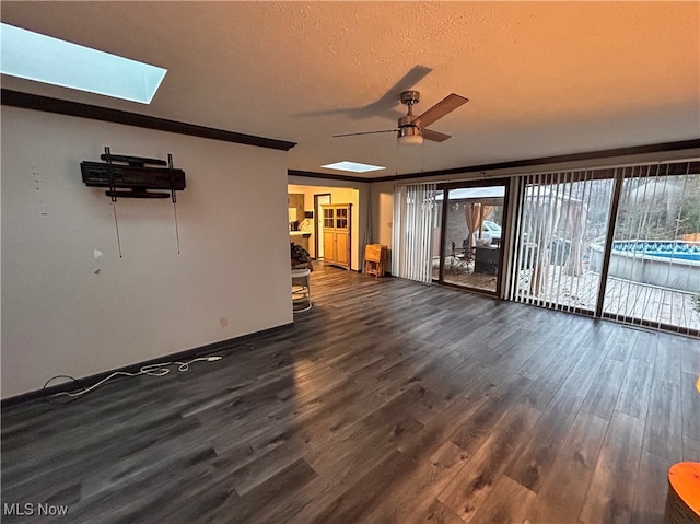 unfurnished living room featuring a textured ceiling, a skylight, ceiling fan, and dark wood-type flooring