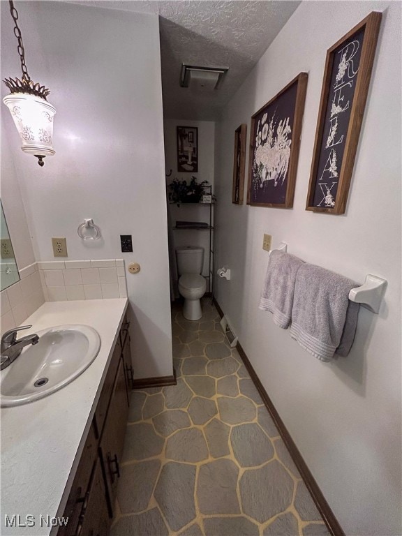 bathroom with vanity, toilet, and a textured ceiling