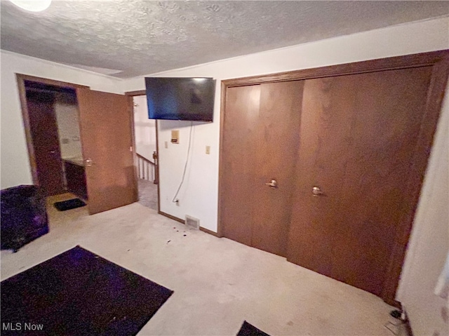 carpeted bedroom featuring a textured ceiling and a closet