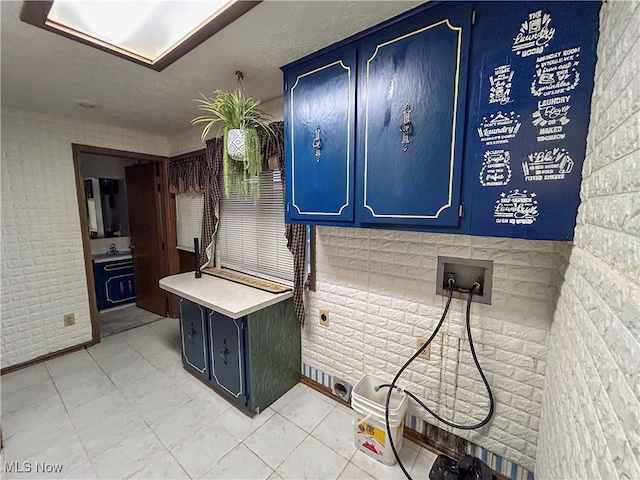 interior space featuring cabinets, hookup for a washing machine, and brick wall