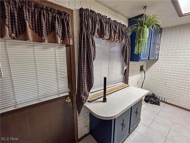 interior space featuring brick wall and light tile patterned flooring