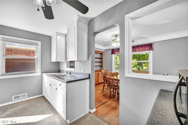 kitchen featuring light hardwood / wood-style floors, ceiling fan, white cabinetry, and sink