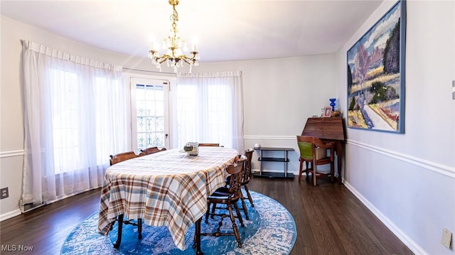 dining area with a wealth of natural light, dark hardwood / wood-style flooring, and a notable chandelier