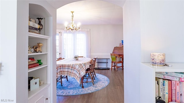 dining space featuring built in shelves, dark wood-type flooring, and a notable chandelier