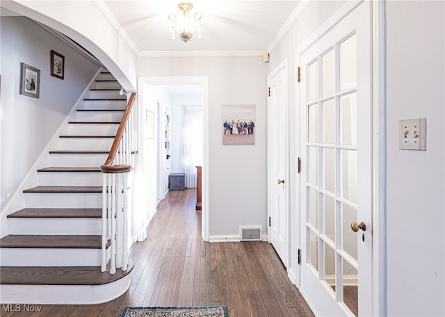 foyer featuring dark wood-type flooring, an inviting chandelier, and crown molding