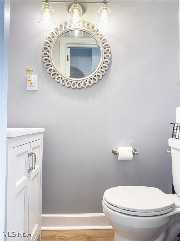 bathroom with wood-type flooring, vanity, and toilet