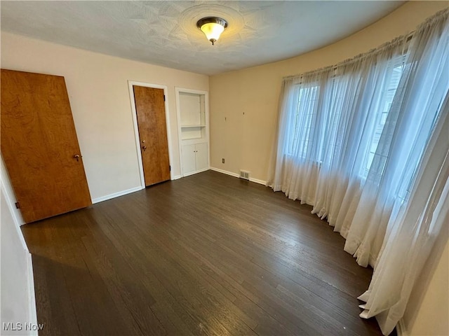 unfurnished bedroom with dark hardwood / wood-style flooring and a closet