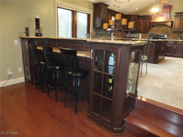 7596 W 130th St, Middleburg Heights, OH 44130 - bar featuring light hardwood / wood-style floors, dark brown cabinetry, range hood, and vaulted ceiling