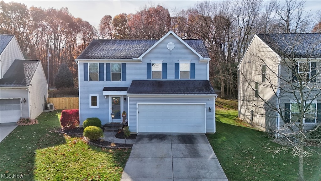 front of property with a front lawn, a garage, and cooling unit