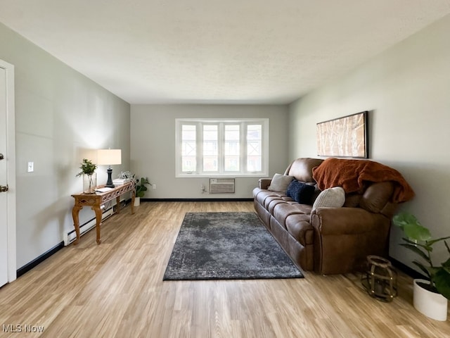 living room with a wall mounted air conditioner, light hardwood / wood-style floors, and a baseboard radiator