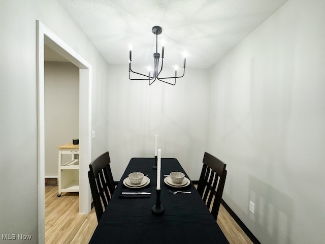 dining space featuring a textured ceiling, light hardwood / wood-style flooring, and a notable chandelier