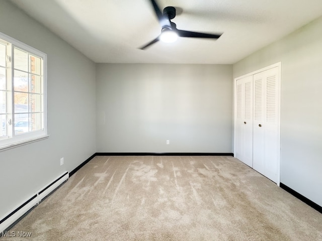 unfurnished bedroom with ceiling fan, baseboard heating, light carpet, and a closet