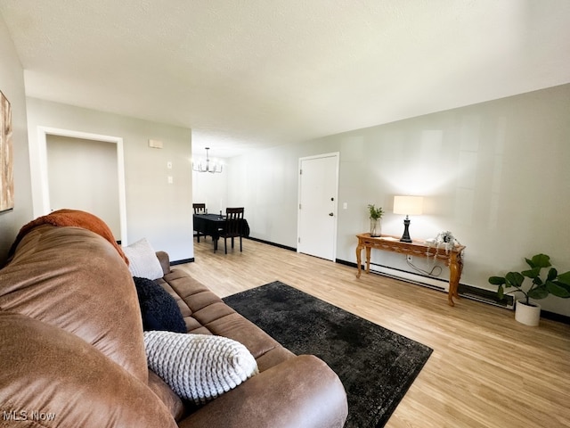 living room with light wood-type flooring, a baseboard radiator, and an inviting chandelier