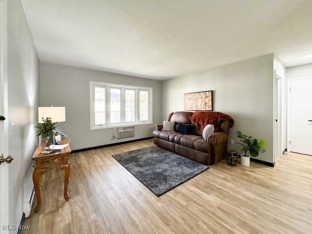 living room with an AC wall unit and light hardwood / wood-style flooring