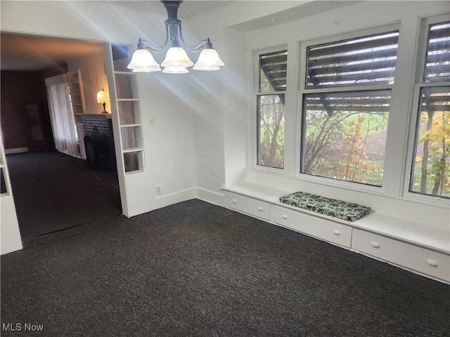 unfurnished dining area featuring an inviting chandelier, dark carpet, and plenty of natural light