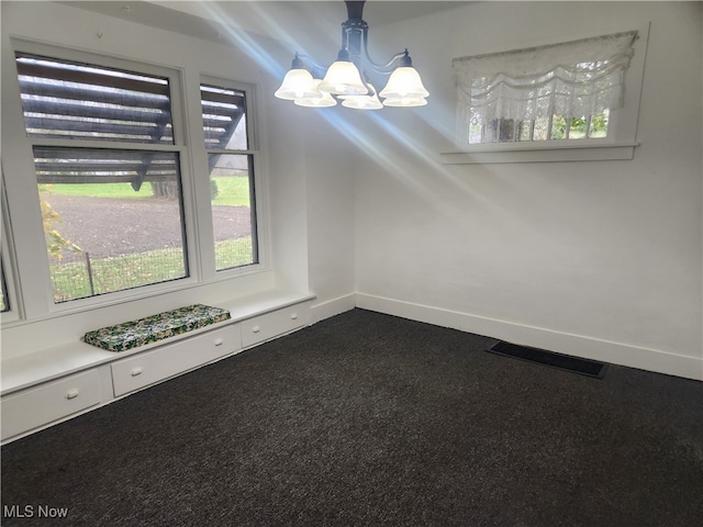 carpeted spare room featuring a notable chandelier