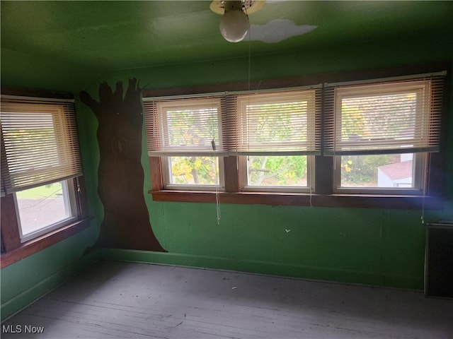 spare room featuring ceiling fan, hardwood / wood-style floors, and a healthy amount of sunlight