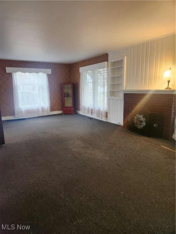 unfurnished living room featuring carpet and a brick fireplace