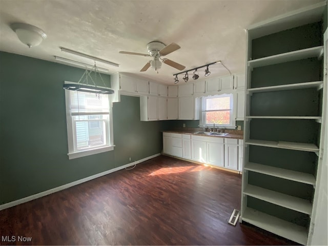 kitchen featuring white cabinetry, sink, ceiling fan, dark hardwood / wood-style floors, and pendant lighting