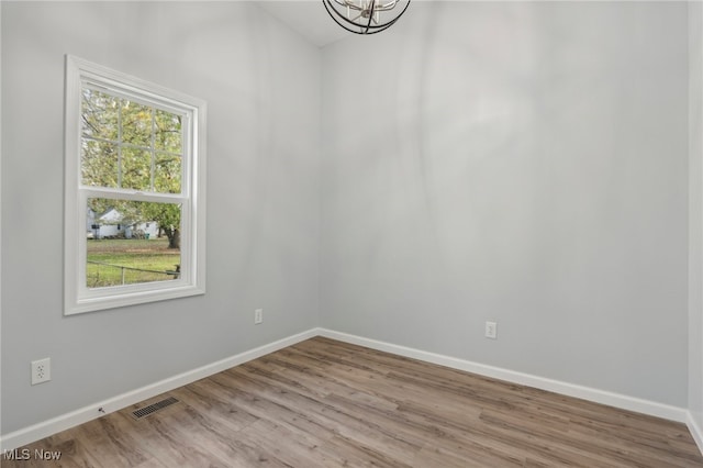 empty room featuring light hardwood / wood-style floors and a chandelier