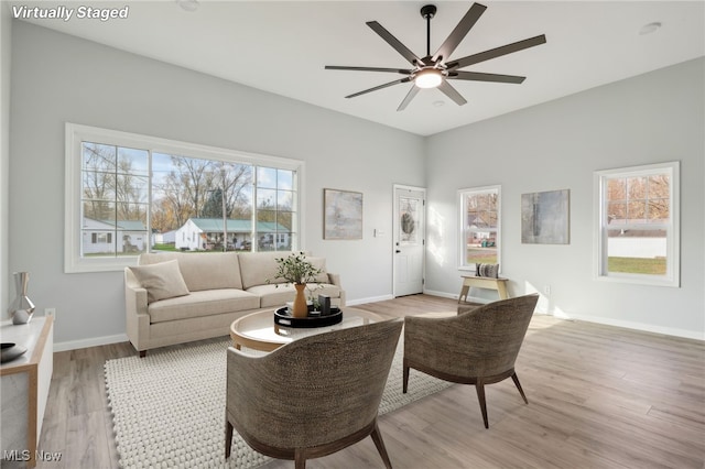 living room with light wood-type flooring, a healthy amount of sunlight, and ceiling fan