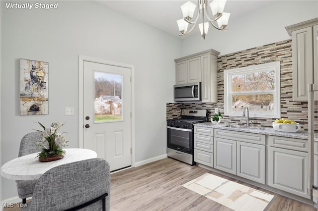 kitchen featuring light hardwood / wood-style floors, appliances with stainless steel finishes, sink, and tasteful backsplash