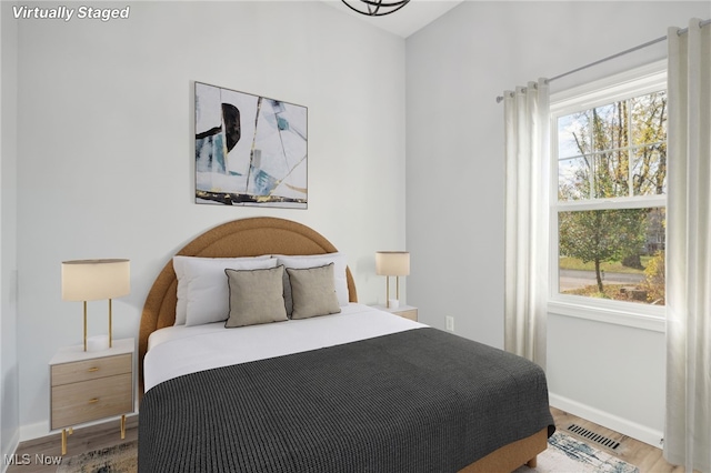 bedroom with hardwood / wood-style flooring and multiple windows