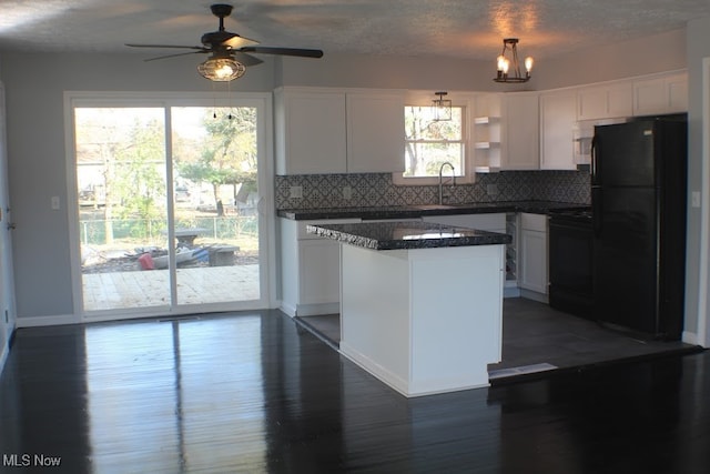 kitchen with tasteful backsplash, white cabinets, black appliances, and a kitchen island