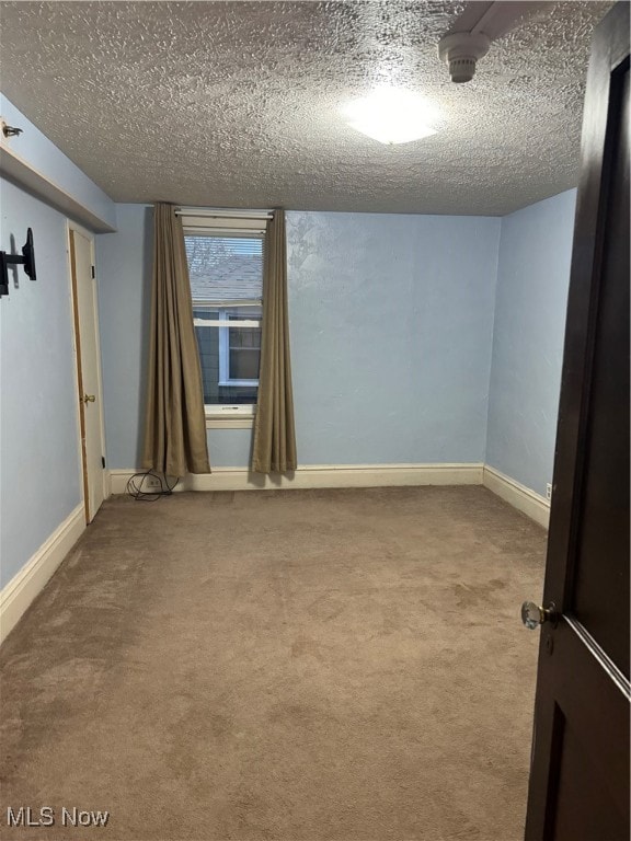 carpeted empty room featuring a textured ceiling