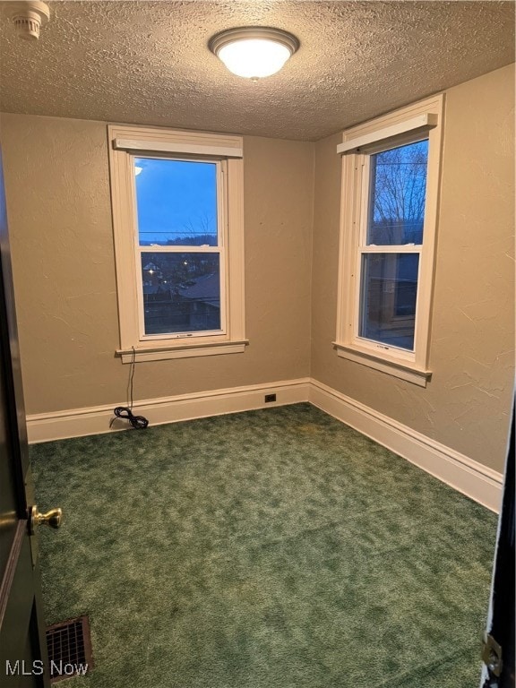 carpeted empty room with a textured ceiling