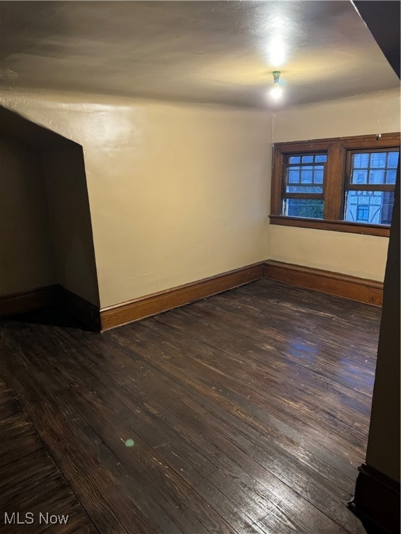 unfurnished room with dark wood-type flooring