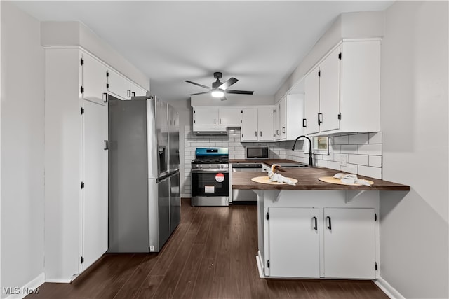 kitchen featuring white cabinetry, sink, kitchen peninsula, appliances with stainless steel finishes, and dark hardwood / wood-style floors