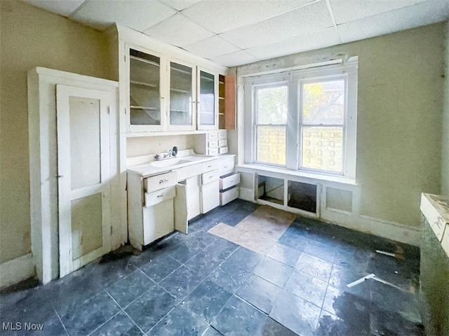 kitchen with white cabinetry, dark tile patterned flooring, and a paneled ceiling