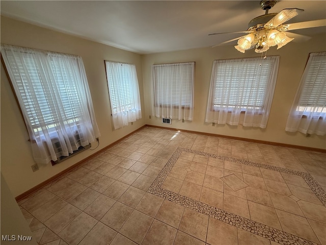 unfurnished room with a wealth of natural light, ceiling fan, and light tile patterned floors