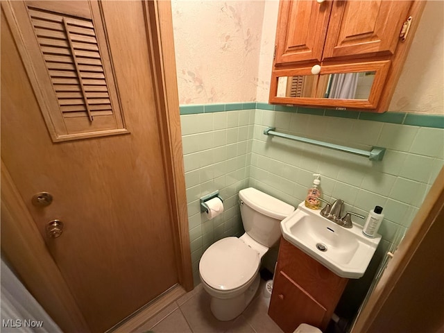 bathroom with tile patterned flooring, sink, tile walls, and toilet