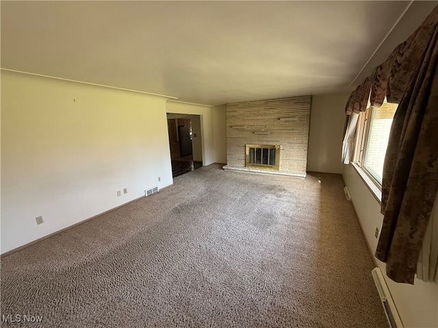 unfurnished living room with a brick fireplace, a baseboard heating unit, and carpet