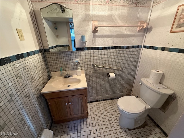 bathroom with toilet, vanity, tile walls, and tile patterned floors