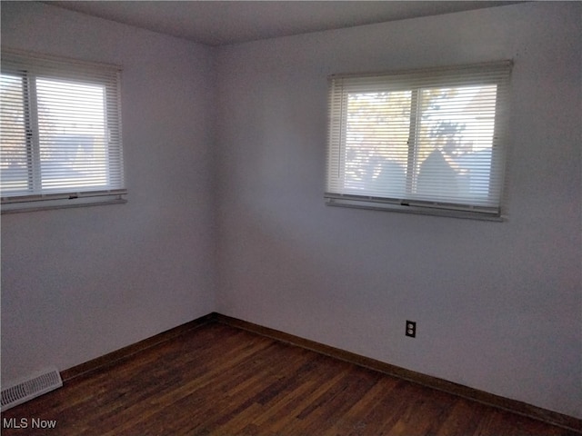 spare room featuring dark hardwood / wood-style floors and plenty of natural light