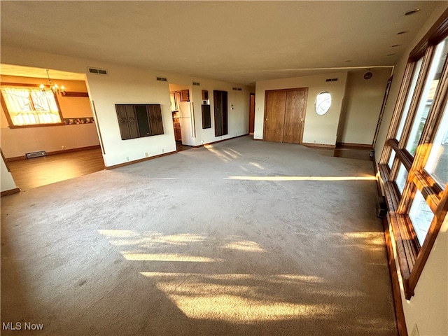 unfurnished living room with carpet floors and a chandelier