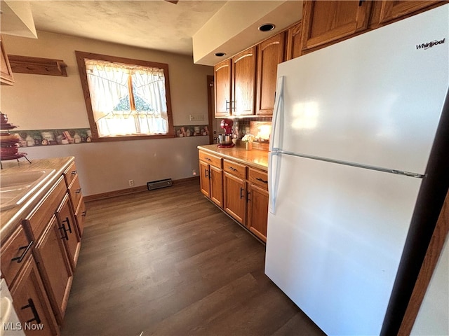 kitchen with dark hardwood / wood-style flooring, white refrigerator, and sink