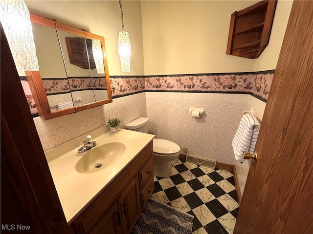 bathroom with tile walls, vanity, and toilet