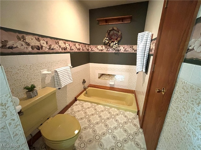 bathroom with toilet, a bathtub, and tile walls